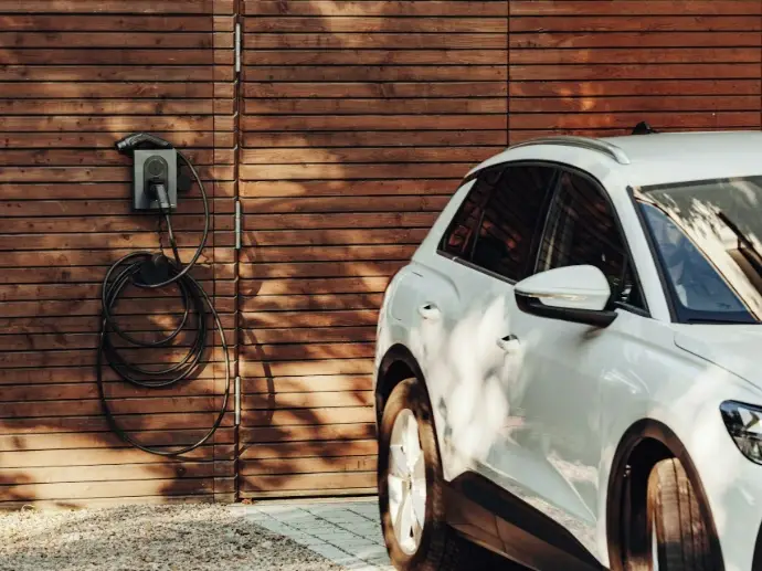 Elektroauto neben einer Wallbox an einer Holzwand