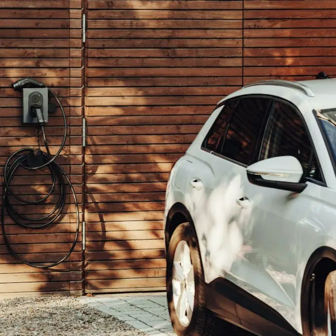 Elektroauto neben einer Wallbox an einer Holzwand