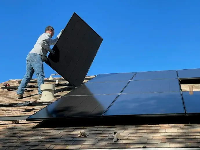 Monteur setzt ein Solarmodul auf einem Hausdach ein